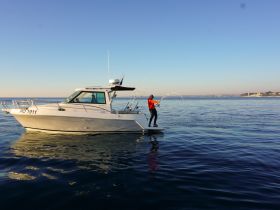 A fisherman casts his line from a boat, enjoying a serene day on the ocean — a perfect scene for fishing enthusiasts.