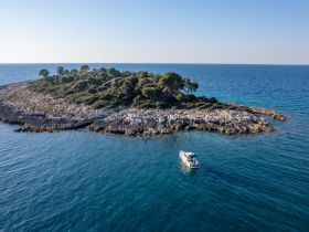 An aerial view of a boat approaching a secluded island, showcasing the stunning coastline and crystal-clear waters — perfect for exploring hidden gems on your next adventure.