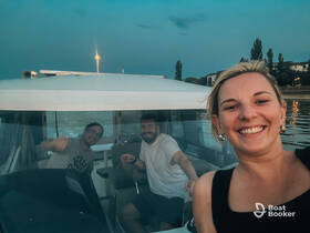 A cheerful group of friends enjoys an evening on the boat, capturing a fun moment together against a serene backdrop.