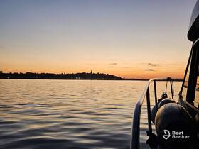 A serene sunset view from the deck of a boat, showcasing calm waters and a distant shoreline — perfect for peaceful evening cruises.