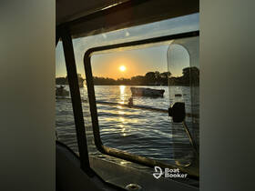 A serene sunset view from inside a boat, showcasing the tranquil waters and silhouettes of other boats in the distance — perfect for peaceful evening cruises.