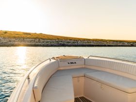A serene view of the interior seating area of a boat, showcasing comfortable cushions and a peaceful water backdrop, perfect for relaxing on a fishing trip.