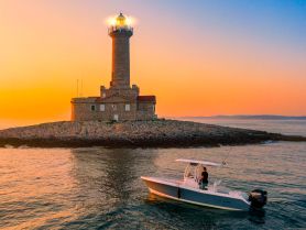 A scenic sunset view featuring a boat near a lighthouse, capturing the serene beauty of coastal adventures.