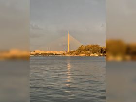 A stunning view of a landmark bridge reflecting in the water at sunset, showcasing the beauty of the surrounding landscape.