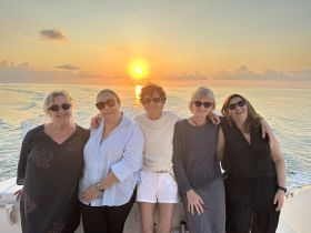 A group of friends enjoys a beautiful sunset on a boat, capturing a perfect moment of joy and camaraderie on the water.
