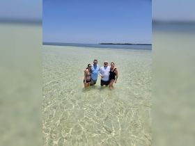 A cheerful group enjoys a sandbar stop, wading in the crystal-clear waters — perfect for fun-filled days under the sun.