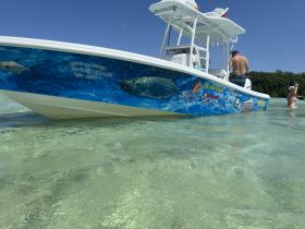 A vibrant fishing boat is anchored in shallow waters with people enjoying the sun and engaging in activities — a perfect scene for a day of adventure on the water.