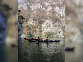 A group of friends enjoys kayaking in a serene waterway surrounded by stunning mountain scenery, perfect for outdoor adventures and nature exploration.