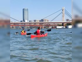 A group of kayakers paddles through the water against a backdrop of a stunning city skyline, showcasing the perfect blend of adventure and urban exploration.
