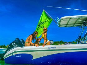 A lively group enjoys a fun moment aboard a boat, showcasing camaraderie and adventure under the sun, with a playful dog joining the festivities.