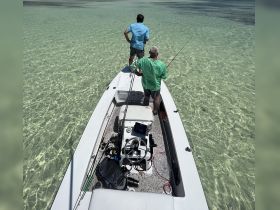 Two anglers enjoy a fishing trip on a boat in crystal-clear waters, showcasing the perfect setting for a day of adventure on the sea.