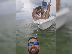 A lively group enjoys a fun day on the water, posing on their boat with smiles and excitement — perfect for memorable summer adventures.