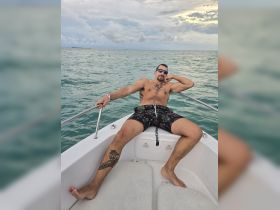 A man relaxes on the bow of a boat, enjoying the ocean view — a perfect moment of leisure on the water.