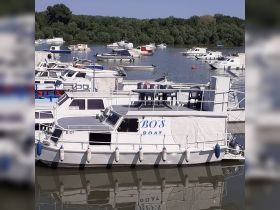 A clear view of 'Bo's Boat' docked among other vessels, showcasing the structure and design of the boat in a serene marina setting.