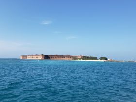 A stunning view of a historic fort surrounded by turquoise waters, showcasing a picturesque coastline — an ideal destination for sightseeing and exploration.
