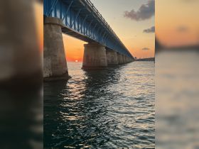 A scenic view of a bridge at sunset, reflecting on the water — a picturesque moment capturing the beauty of the evening sky.