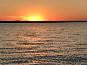 A stunning sunset over calm waters, creating a picturesque backdrop perfect for evening boat cruises or relaxation by the shore.
