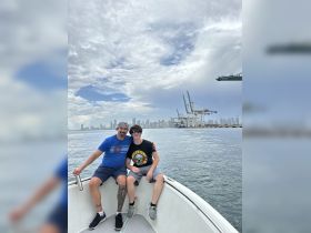 A father and son enjoy a scenic boat ride with a stunning city skyline in the background, perfect for family outings on the water.