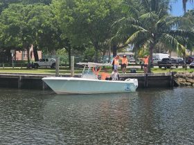 A lively group of friends waves from a boat at the dock, ready for a day of fishing and fun on the water.