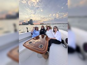 A group of friends enjoys a beautiful sunset on a boat, capturing joyful moments together — perfect for celebrations and memorable outings on the water.