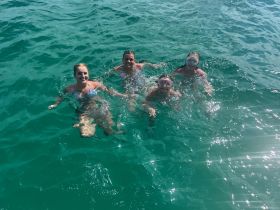 A joyful group of friends enjoys a refreshing swim in crystal-clear waters, capturing the essence of a perfect day on the water.