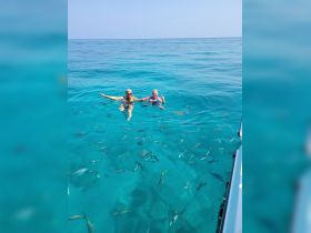 Two friends enjoy a refreshing swim in crystal-clear waters, surrounded by colorful fish — a perfect moment for underwater exploration and fun.