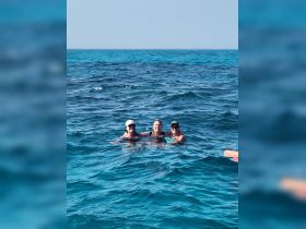 A joyful group of friends enjoys a refreshing swim in the vibrant turquoise waters, capturing the essence of a perfect day on the water.