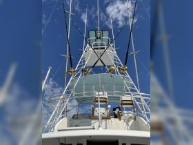 A detailed view of the helm area on a fishing boat, showcasing the seating and console setup under a clear blue sky, perfect for fishing adventures.