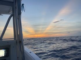 A serene view from a boat at sunset, showcasing the tranquil ocean and vibrant sky — perfect for peaceful evening cruises.