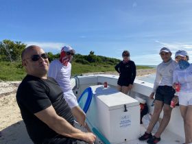 A group of friends enjoys a sunny day on a boat, relaxing with drinks and soaking in the beautiful surroundings — perfect for a fun day out on the water.