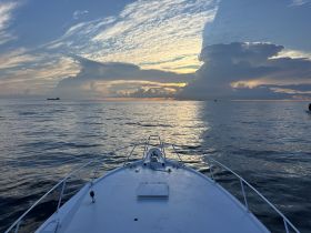 A serene view from the front of a boat, capturing the tranquil waters and a stunning sunset backdrop — perfect for peaceful evening cruises.