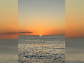 A serene sunset over calm waters, creating a picturesque backdrop for evening boat cruises and relaxation on the water.