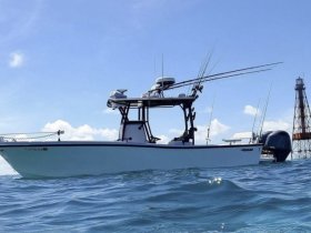 A sleek speedboat glides through the water, showcasing its design and fishing gear, perfect for a day out on the ocean.