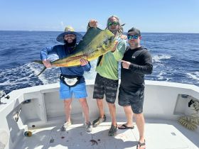 Three friends proudly display their impressive catch while fishing on a boat, capturing the thrill of a successful day on the water.