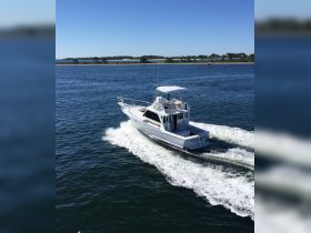 A sleek speedboat navigates through clear waters, showcasing its design and performance while underway. Perfect for fishing or leisure outings.