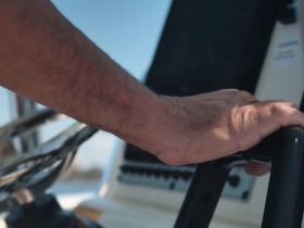 A close-up view of a hand on the helm of a boat, showcasing the control console — an essential part of navigating the open waters.