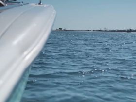 A close-up view of a boat's side gliding through calm waters, showcasing the sleek design and tranquil surroundings — perfect for a day on the water.
