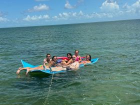 A lively group enjoys a sunny day floating on a colorful mat in the clear waters, perfect for summer fun and relaxation.