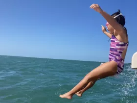 A child joyfully jumps into the sparkling ocean, capturing the excitement of water activities during a fun day on the boat.
