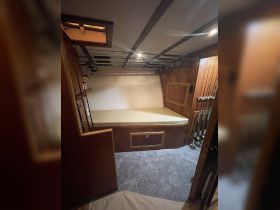 Interior view of a cozy boat cabin featuring a padded seating area and fishing rods neatly stored, perfect for anglers looking to relax while on the water.