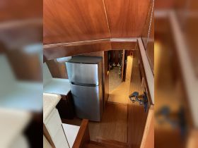 Interior view of a boat's kitchen area featuring a refrigerator and wooden cabinetry, showcasing the cozy and functional design of the cabin space.