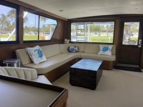 A cozy interior view of a boat's lounge area featuring comfortable seating and decorative pillows, perfect for relaxing while on the water.