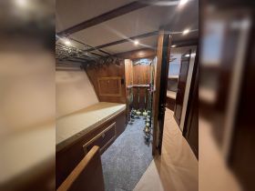 Interior view of a fishing boat cabin featuring organized fishing rods and a comfortable seating area, perfect for anglers preparing for their next adventure.
