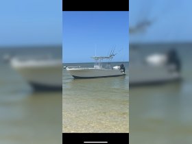 A sleek speedboat anchored in shallow waters, showcasing its fishing gear and ready for a day on the water.