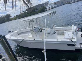 A sleek center console boat docked by the water, showcasing its clean lines and functional design, perfect for fishing or day trips.