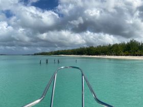A stunning view of a tranquil beach with clear turquoise waters and a picturesque coastline, perfect for island hopping adventures.