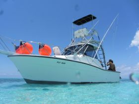 A group enjoys a sunny day on a fishing boat in clear turquoise waters, perfect for aquatic adventures and relaxation.