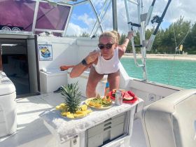 A woman enjoys a delicious spread of snacks, including pineapple, watermelon, and nachos, aboard a boat — perfect for a relaxing day on the water.