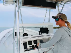 A woman at the helm of a boat, showcasing the interior console and steering area — perfect for those looking to navigate the waters with confidence.