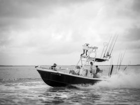A dynamic shot of a fishing boat in action, with crew members enjoying the thrill of the ride on the water — perfect for adventure seekers and fishing enthusiasts.